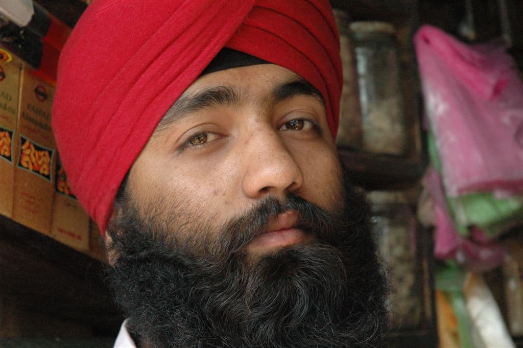 An Afghan Sikh shopkeeper in a red turban