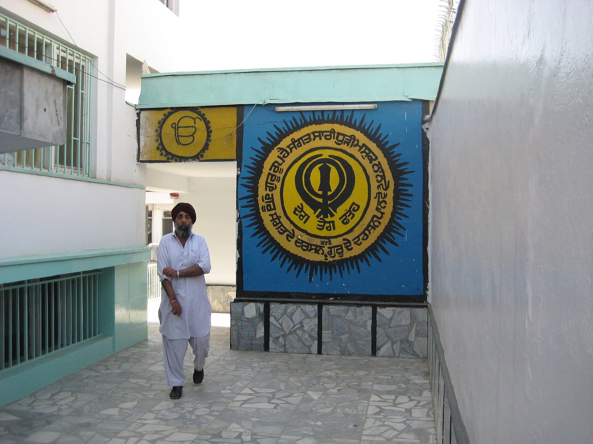 A Sikh man walks past the painted khanda mural in the courtyard of Gurdwara Karte Parwan, Kabul